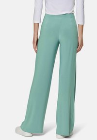 Mint green wide-leg pants made from soft fabric, featuring a smooth waistband and a flowing design. Finished with a straight hem and subtle drape.