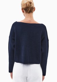 Granatowy sweter z dzianiny o szerokim dekolcie, krótkim kroju i opadających ramionach. Tkanina ma lekko teksturowane wykończenie.