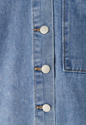 Denim jurk van lichtblauwe stof, vijf metalen knopen met gegraveerde tekst en een borstzak met een effen rand.