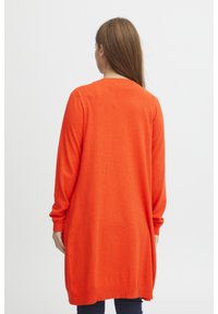 Long cardigan orange avec des manches longues et une coupe droite. Fabriqué en tissu doux, avec un col rond et des poignets côtelés.