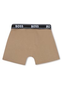 Μπεζ μπόξερ από απαλό ύφασμα, με μαύρη ελαστική μέση που φέρει το λογότυπο "BOSS" και άσπρες ρίγες, μήκους μέχρι τη μέση του μηρού.