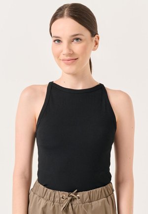 Schwarzes, geripptes Tanktop mit rundem Ausschnitt und dünnen Trägern, kombiniert mit beigen Jogginghosen mit einem gerafften Bund.