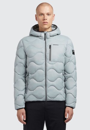 Giacca imbottita blu chiaro con motivo a onde, chiusura con zip e cappuccio. Presenta tasche frontali e una tasca sul petto con logo.