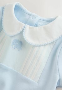 Lyseblå kjole med en hvid krave, plisseret design og et broderet elefantmotiv. Stoffet virker blødt og glat.