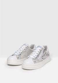 Bílé tenisky se stříbrnými akcenty, semišovými bočními panely a šněrováním, s bočním zipem a texturovou gumovou podrážkou.