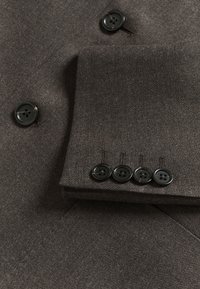 Brown textured fabric with black buttons; features two buttons on the lapel and four buttons on the cuff.