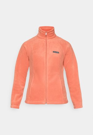 Koraļļu vilnas jaka ar augstu apkakli, pilnu rāvējslēdzēju priekšā un raglanu piedurknēm. Iekļauts neliels logotipa iešuvums kreisajā krūtīs. Mīksta tekstūra.