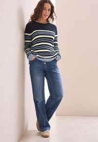 Blå och marinrandig tröja med ribbad textur, kombinerad med ljusblå denimjeans. Outfitten har en avslappnad passform och ett ledigt design.