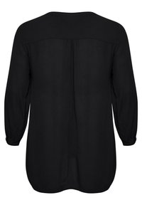 Schwarze Bluse mit langen Ärmeln. Weicher Stoff, runder Ausschnitt und Faltendetails auf der Rückseite. Gerundeter Saum mit leicht elastischen Bündchen.