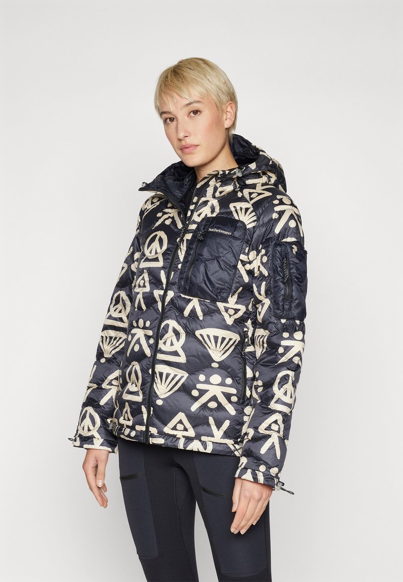 Casaco puffer azul marinho com padrões abstratos em bege, bolsos com fecho éclair e capuz, apresentando textura acolchoada e uma bainha ajustável para maior aquecimento.