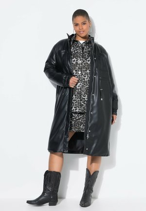 Black faux leather coat with a zip front, long sleeves, and elastic cuffs, layered over a leopard print shirt dress and black cowboy boots.