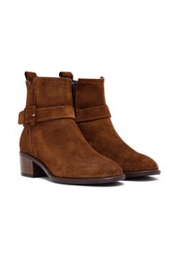 Stivali ankle in suede marrone con punta rotonda, cerniera laterale e una fascia decorativa con fibbia. Tacco basso in blocco.