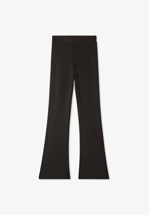 Pantaloni neri a zampa d'elefante realizzati in tessuto elasticizzato, caratterizzati da un motivo a pois bianchi. Texture liscia, vita elastica e senza hardware visibile.
