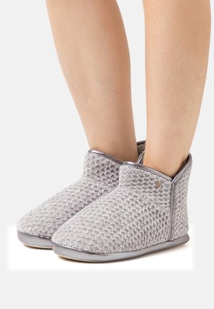 Gray knitted slippers with a textured design, soft upper, and a smooth, silver-toned sole. Includes a small metallic accent on the side.