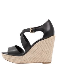 Sandalo wedge in pelle nera con cinturini incrociati, suola intermedia in juta intrecciata e un accento in metallo dorato sulla fibbia. Design con punta aperta.