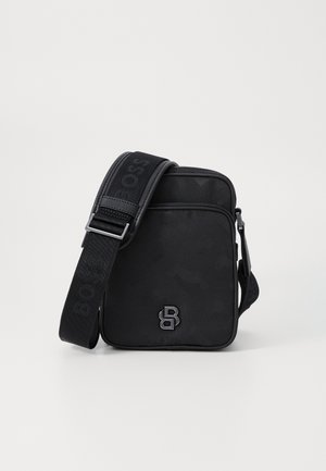 Borsa a tracolla nera con un design elegante, realizzata in tessuto testurizzato. Presenta un logo audace e una tracolla regolabile con branding. Compatta e moderna.
