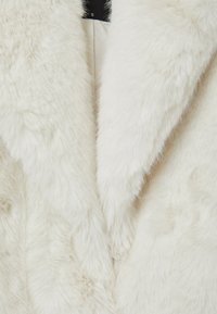 Weißer Kunstpelzstoff mit einer weichen, dicken Textur. Besitzt ein plüschiges, flauschiges Aussehen und ein klassisches Kragen-Design.