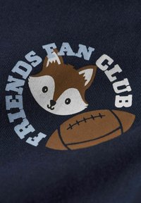 T-shirt bleu marine arborant un motif imprimé d'une tête de renard et d'un ballon de football, avec le texte « CLUB DES FANS DE FRIENDS » en bleu clair et blanc.