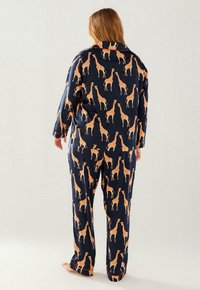 Navy pajama set made of soft fabric featuring a repeated giraffe print in orange. Includes a long-sleeve shirt and matching pants.