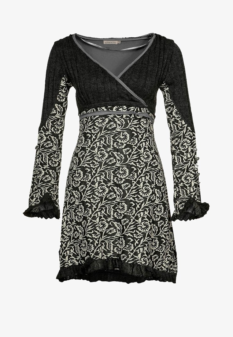 Svart och vit blommönstrad klänning med långa ärmar, volangdetaljer vid ärmsluten, en V-ringning och en figurnära midja. Tillverkad av texturerat stickat tyg.