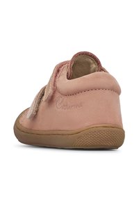 Zapato para bebé de ante rosa con punta redondeada, tira de velcro y suela de goma texturizada, que cuenta con una superficie suave y un sutil detalle de logo.