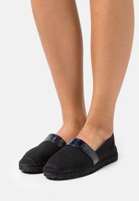 Zwarte espadrilles met een band van lakleer, voorzien van een gevlochten juten zool en een glad canvas bovenwerk. Laag profiel ontwerp.