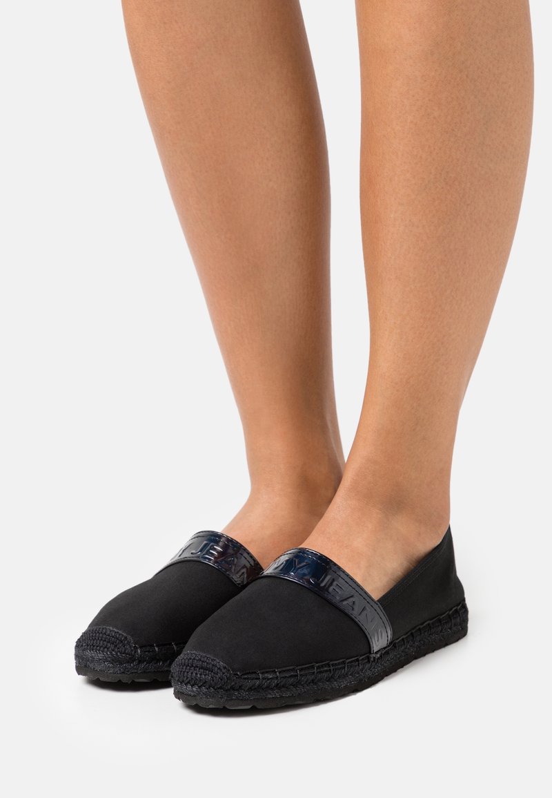 Zwarte espadrilles met een band van lakleer, voorzien van een gevlochten juten zool en een glad canvas bovenwerk. Laag profiel ontwerp.
