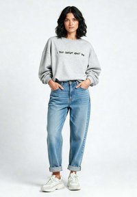 Felpa grigia oversized con il testo nero "HO PARLATO DI TE A CHATGPT", abbinata a jeans chiari a vita alta e sneakers bianche.