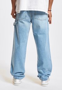 Lyseblå denim cargo bukser med afslappet pasform, der har sidelommer, synlige sømme og en tapered ankel-design.