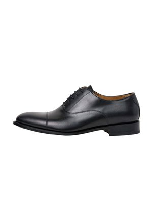 Zapato Oxford de hombre de cuero negro con cordones cerrados, puntera con tapeta y tacón bajo, mostrado de perfil lateral sobre fondo blanco.