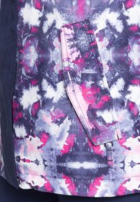 Farbenfrohe Jacke mit einem lila, rosa und weißen abstrakten Muster, das auf einer Seite eine auffällige Taschenöffnung und einen strukturierten Stoff aufweist.