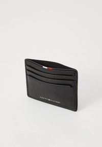 Black leather cardholder with multiple slots, textured finish, and embossed logo. Compact rectangular shape with a minimalist design.