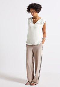 Light gray textured top with a V-neck and cap sleeves, paired with beige wide-leg trousers featuring black side stripes.