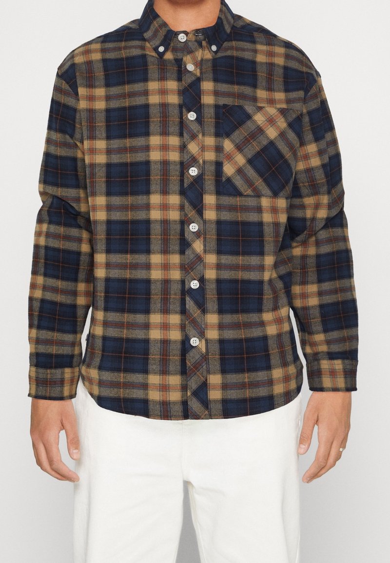 Camisa a cuadros con colores azul, beige y óxido, diseño abotonado, cuello y bolsillo frontal; mangas largas con puños abotonados.