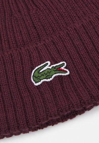 Бургундска рибена плетена шапка с зелен логотип на крокодил на бял патч; мека текстура и детайл с прегънат ръб.