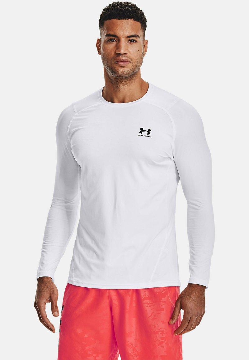 Weißes Langarm-Sportshirt mit Rundhalsausschnitt und schwarzem Under Armour-Logo auf der linken Brust, aus einem glatten, dehnbarem Stoff gefertigt.