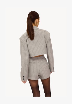 Grauer kurz geschnittener Blazer mit Nadelstreifen und weiten Ärmeln, kombiniert mit passenden, hoch taillierten Shorts, mit Knopfakzenten und einem strukturierten Design.