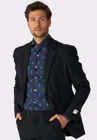 Crna sako jakna preko mornarsko plave košulje s zelenim uzorkom drveća. Košulja ima ovratnik i gumbe, s etiketom na rukavu.