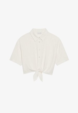 Kuttet kortermet skjorte i lys beige lin, med knapper foran og knyting nederst. Glatt tekstur med klassisk krage.