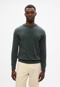 Mørkegrøn sweater i et blødt, tekstureret stof. Har en rund halsudskæring og ribbede manchetter og kant. Lille logo-detalje på brystet.