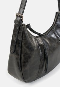 Borsa a tracolla in pelle nera con texture liscia, design curvo, tracolla regolabile e chiusura con zip. Presenta una leggera lucentezza e accenti minimalisti.