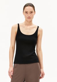 Schwarzes Ripp-Tanktop mit breiten Trägern, das eine taillierte Silhouette und eine glatte Textur aufweist. Kombiniert mit braunen Hosen.