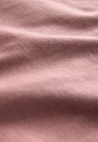Tessuto rosa con una consistenza morbida e liscia, caratterizzato da un delicato pattern intrecciato e una leggera lucentezza, che si drappeggia dolcemente.