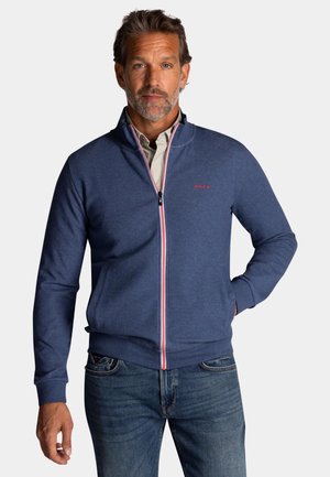 Marineblauwe ritssluiting sweatshirt met een hoge kraag, een contrasterende rode en witte rits en voorzakken, gemaakt van een zachte katoenmix.