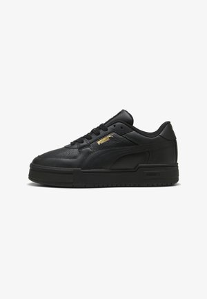 Sorte sneakers i læder med en tekstureret finish, flad gummisål, polstret krave og gyldne logoaccenter på ydersiden.