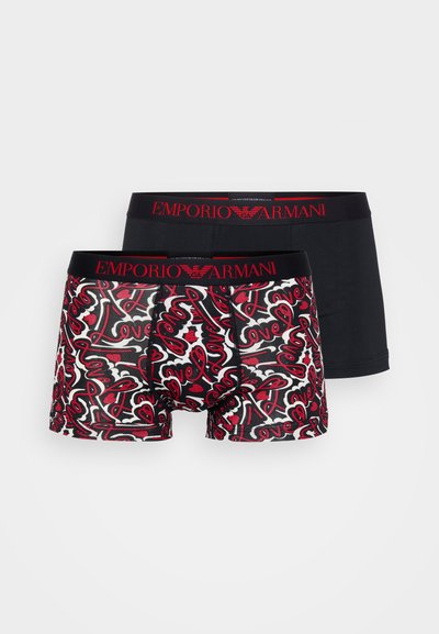 Deux paires de boxers Emporio Armani : une noire avec un logo rouge, une autre à motifs de cœurs rouges et blancs sur fond noir.