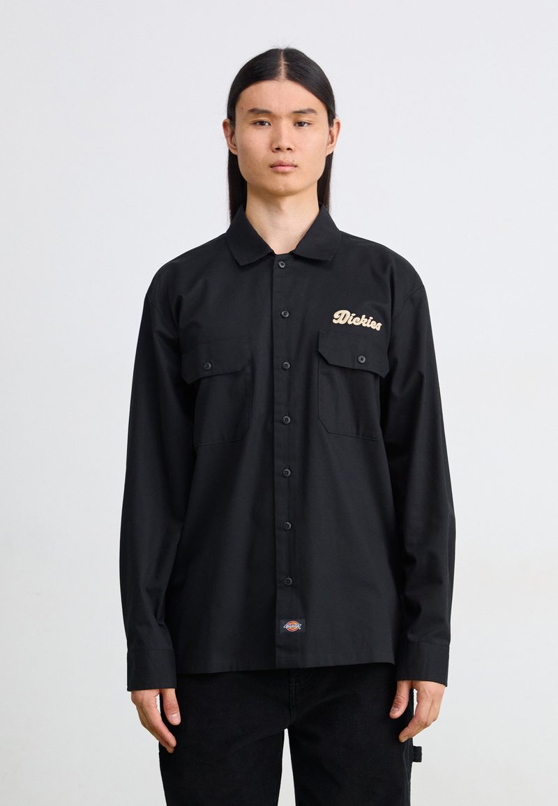 Camicia nera con bottoni, dotata di due tasche frontali e logo in beige. Realizzata in tessuto liscio e leggero; presenta maniche lunghe e colletto.
