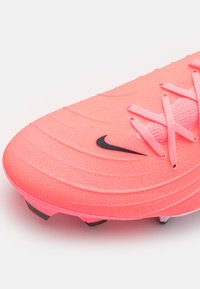 Scarpette da calcio sintetiche rosa con superficie testurizzata, logo Nike nero e lacci abbinati, dotate di tacchetti stampati sulla suola per una migliore trazione.