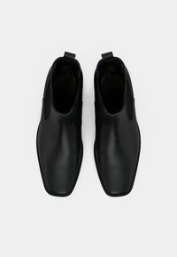 Černé kožené Chelsea boty s hladkým povrchem, obdélníkovou špičkou a elastickými bočními panely. Obsahují poutka pro snadné obouvání.