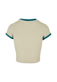 Cream short-sleeve crop top with teal ribbed neckline and sleeve cuffs. Smooth cotton fabric, fitted design with a rounded hem.